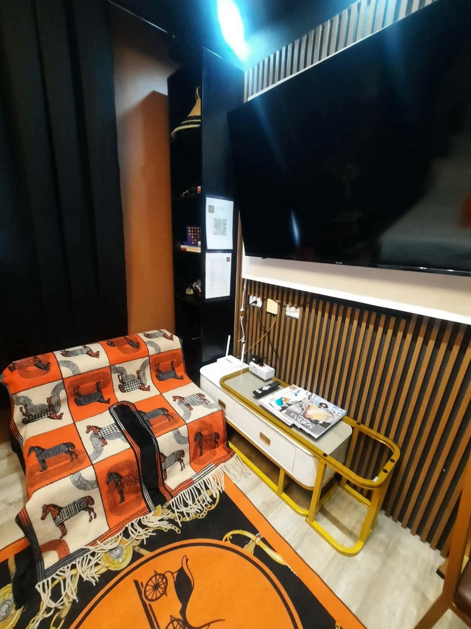 Un soggiorno moderno con un divano, una televisione, un tavolino con riviste e una TV a parete.
