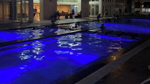 A nighttime scene of a building with a pool area illuminated by blue lighting. - Cappuccino Studio in Mesavirre Garden Bacolod (Bacolod)