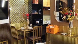 A modern dining area with a wooden table set for two, a kitchen in the background, and a decorative mirror on the wall. - Cappuccino Studio in Mesavirre Garden Bacolod (Bacolod)