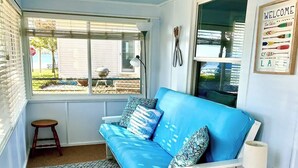 Ein gemütlicher Winkel mit einem blauen Sofa, einem Teppich mit Muster und einem kleinen Tisch mit einer Lampe und Dekoration.