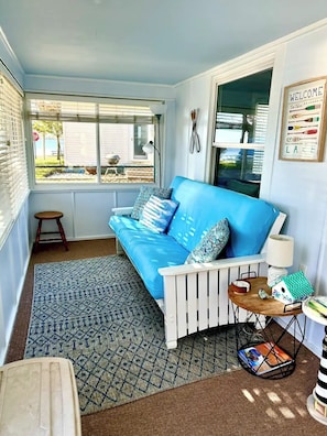 A cozy corner with a blue sofa, patterned rug, and a small table with a lamp and decorative items. - Spacious 4-bedroom house in lovely Manitou Beach-Devils Lake with AC (Manitou Beach-Devils Lake)
