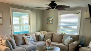 Ein Wohnzimmer mit Ecksofa, Couchtisch und Deckenventilator.