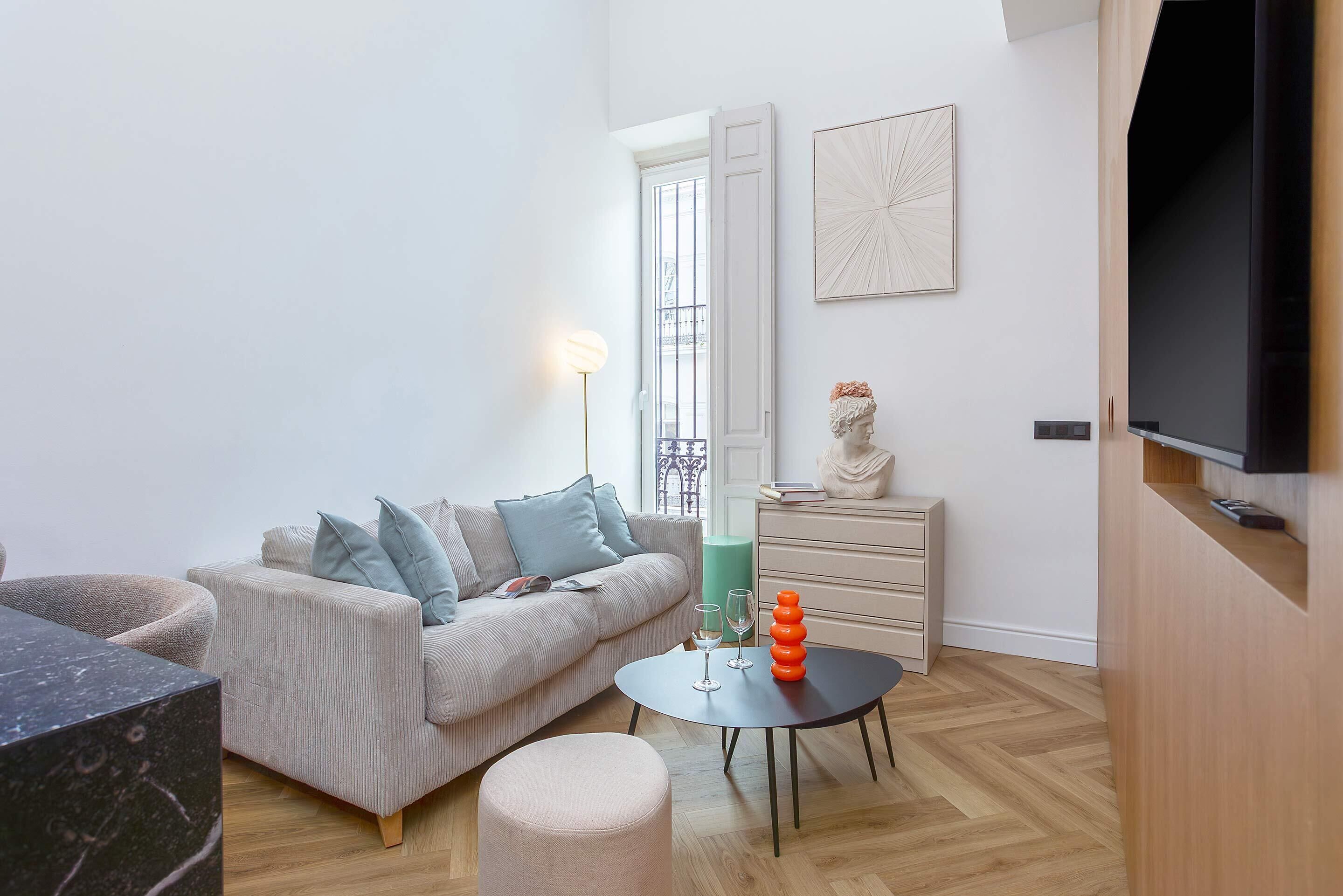 Una sala de estar moderna con un sofá, una mesa de centro, un televisor y una estatua.