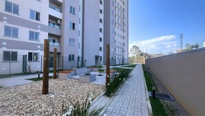 A multi-story residential building with balconies, a paved courtyard, and a landscaped garden area. - Solarium Beach Club -Apartamento T1.1105 (Itapoá)