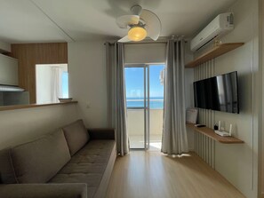 A modern living room with a sofa, a flat-screen TV, and a ceiling fan. - Solarium Beach Club -Apartamento T1.1105 (Itapoá)