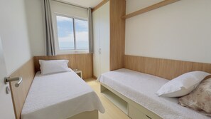A bedroom with two single beds, a wooden headboard, a window with curtains, and a wardrobe. - Solarium Beach Club -Apartamento T1.1105 (Itapoá)