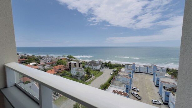 A coastal residential area with buildings, a parking lot, and a view of the ocean. - Solarium Beach Club -Apartamento T1.1105 (Itapoá)