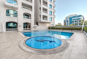 Ein modernes Gebäude mit Schwimmbad, das ein Haifischdesign aufweist, umgeben von einer gefliesten Terrasse.