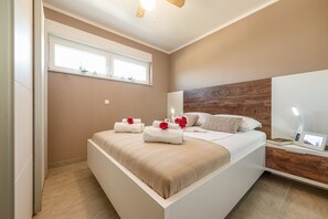 Un dormitorio moderno con una cama grande, un cabecero de madera, una mesita de noche con una lámpara y una ventana con vistas.