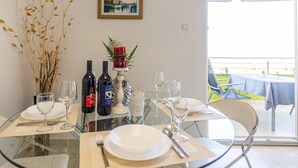 Mesa de comedor servida con copas de vino, platos y cubiertos, con vista al exterior.