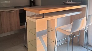 Una cocina moderna con encimera de madera y dos sillas blancas.