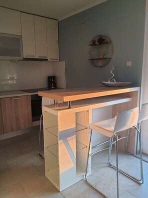 A modern kitchen with a wooden countertop and two white chairs.