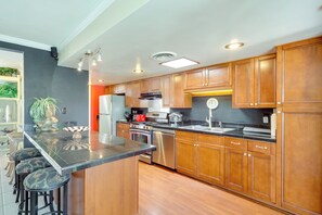 A modern kitchen with wooden cabinets, stainless steel appliances, and a central island with stools. - 4 Mi to Indian Wells Tennis: Home w/ Mtn Views! (Palm Desert)