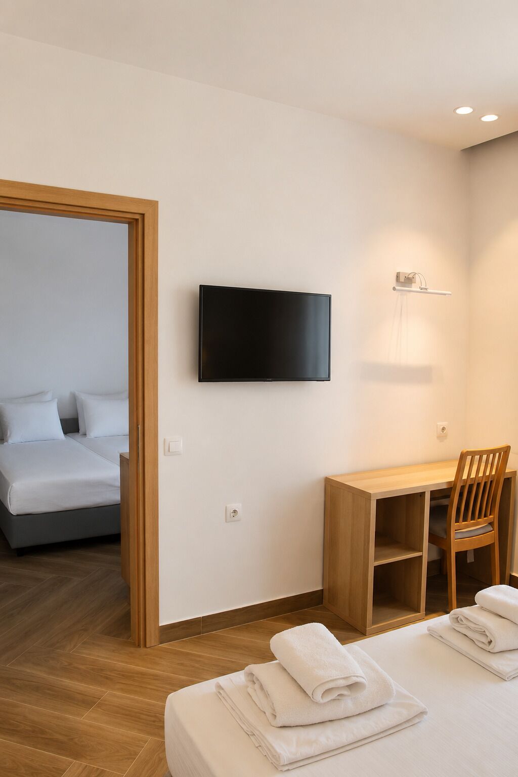 Hotellihuone, jossa on sänky, työpöytä, tuoli, televisio ja suihku.