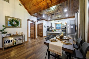 Eine moderne Küche mit Holzschränken, einem Edelstahl-Kühlschrank und einem Essbereich mit Holztisch und Stühlen.