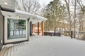 A modern outdoor deck area with a glass enclosure, wooden deck, and a covered seating area.