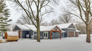 Ein zweistöckiges Haus mit Garage und überdachter Veranda, dessen Hof mit Schnee bedeckt ist.