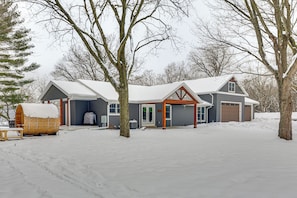 A two-story house with a garage, a covered porch, and a snow-covered yard.