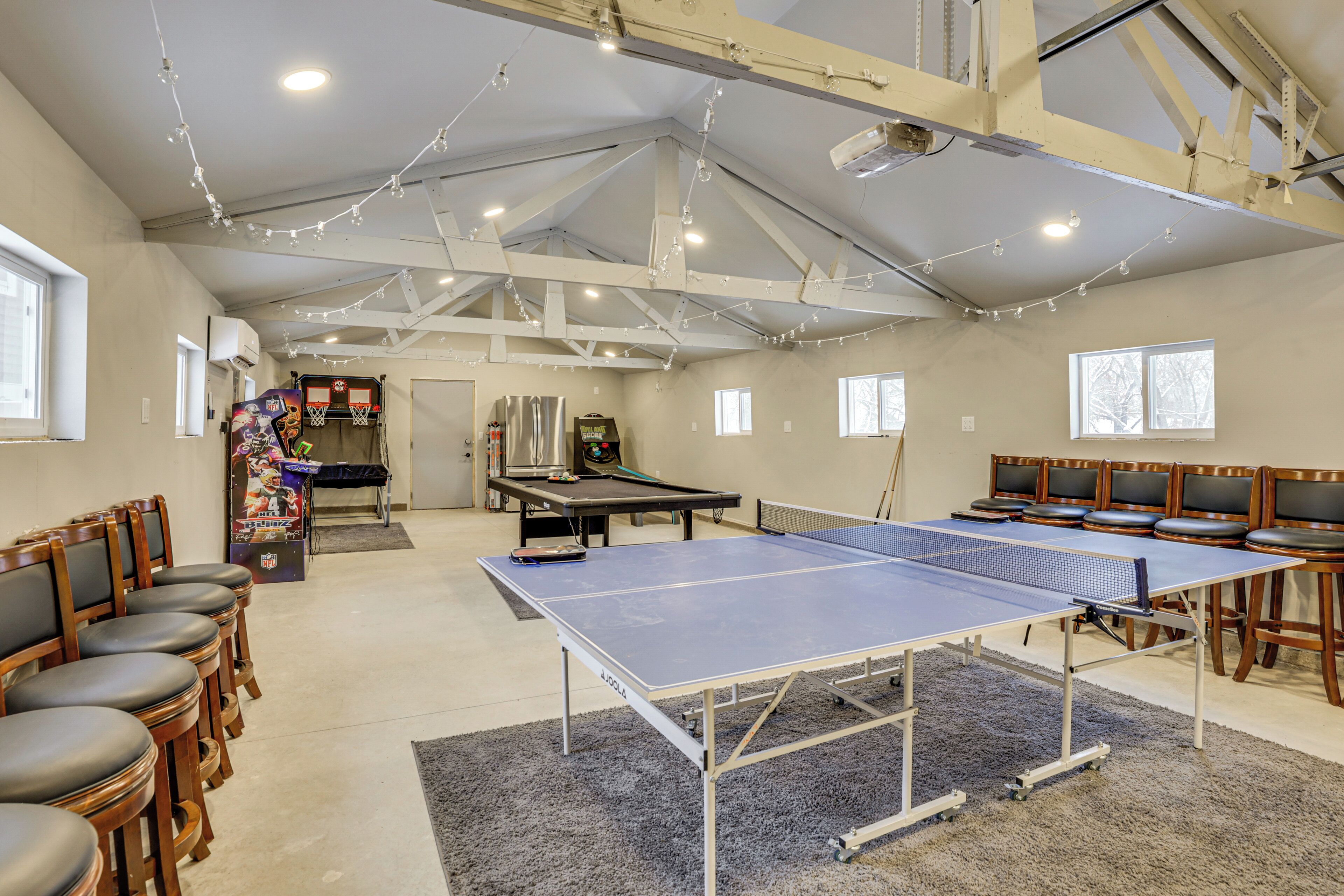 Un espacio interior amplio con mesa de ping pong, asientos y aro de baloncesto.