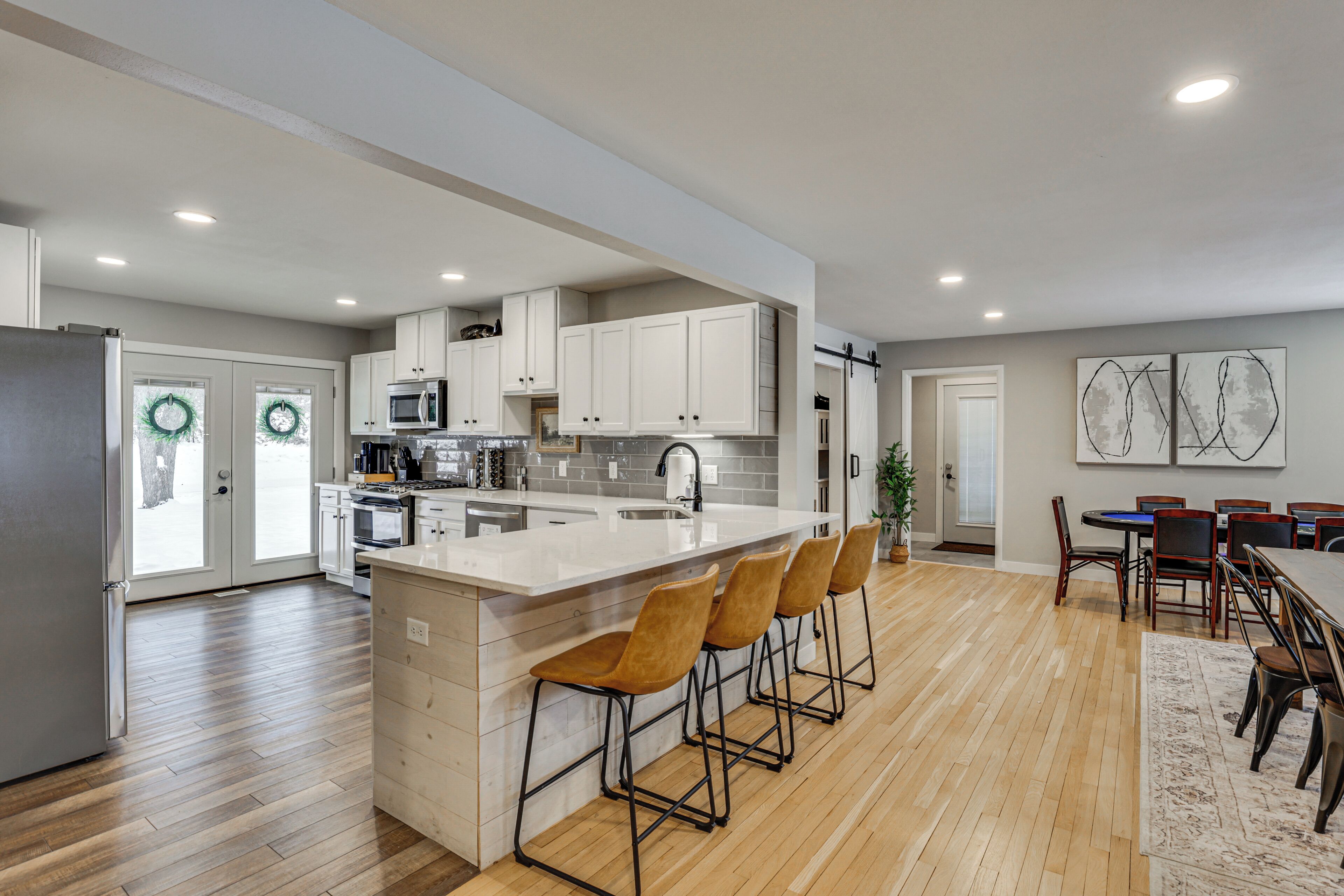 A modern kitchen with a central island, bar stools, and a dining area with a table and chairs.