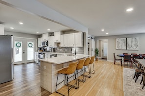 A modern kitchen with a central island, bar stools, and a dining area with a table and chairs.