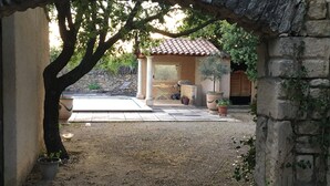 A courtyard with a stone wall, a tiled patio, and potted plants. - Country House 'Mas Les Coutilles' with Mountain View, Private Pool and Wi-Fi (Cabrières-d'Avignon)