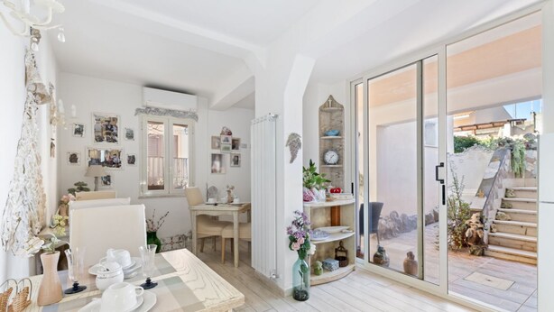 Ein geräumiges Zimmer mit Essbereich, einer großen Schiebeglastür, die auf einen Balkon führt, und einer Wand mit verschiedenen Dekorationen.