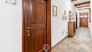 Ein Korridor mit einer Holztür, Steinböden und gerahmten Bildern an der Wand.