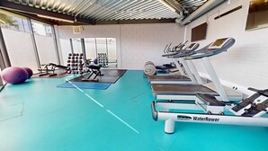 A gym with exercise equipment, a water rower, and a wall-mounted weight rack. - iQ Student Quarter in Salford (Salford)