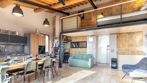Eine geräumige Küche mit Essbereich, einer Treppe zu einer oberen Ebene und einem gemütlichen Wohnbereich mit Sofa und Schaukelstuhl.