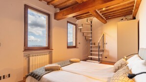 Ein Schlafzimmer mit Bett, Heizkörper, Fenster und Treppe sowie einem Kleiderschrank.