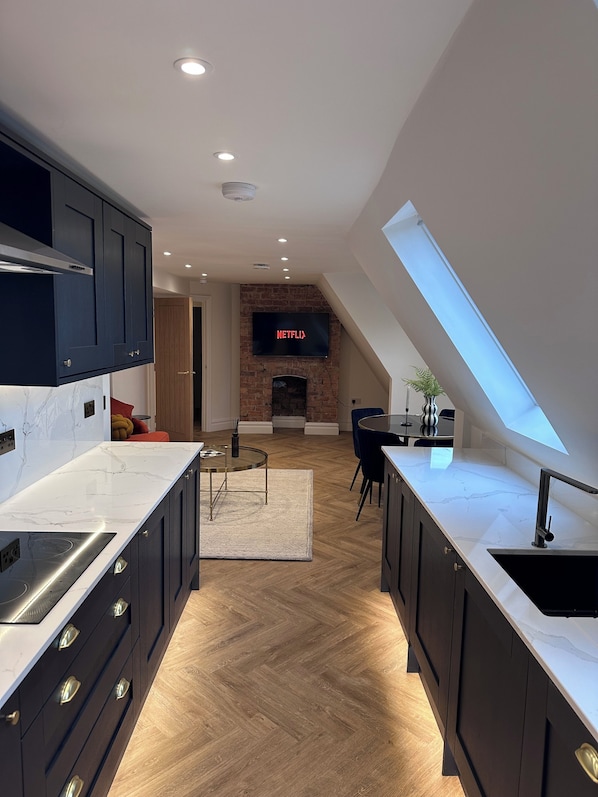 A modern kitchen with dark cabinets, a marble countertop, and a built-in oven.