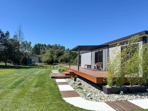 A modern house with a wooden deck, a patio, and a garden area with plants and a pathway.