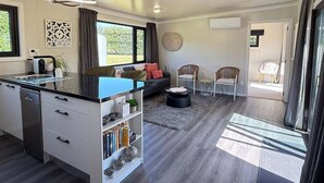 A modern kitchen with a central island, a dining area with a sofa and chairs, and a living area with a sofa and a coffee table. - Private 2BR Haven – West Melton - Haven on Halkett (Christchurch)