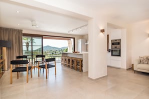 A modern kitchen with a large island, a dining area with chairs, and a sofa.
