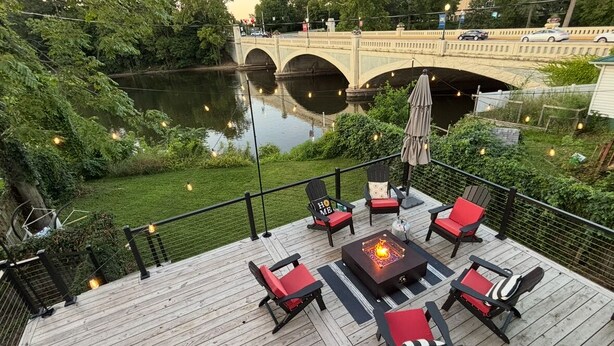 A deck with outdoor seating, a fire pit, and a view of a bridge over a river. - Newly remodeled 3 bedroom, 1.5 bath home with a river view in downtown Elkhart.  (Elkhart)