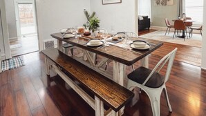 A dining area with a wooden table, white chairs, and a bench. There is a ceiling light fixture above the table. - Newly remodeled 3 bedroom, 1.5 bath home with a river view in downtown Elkhart.  (Elkhart)