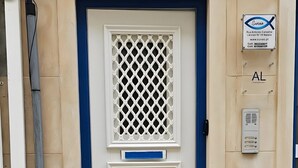 Une entrée d’immeuble avec une porte bleue, portant le numéro 19, et un panneau indiquant un espace de stationnement.