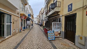 Une rue étroite bordée de boutiques et d’un restaurant.