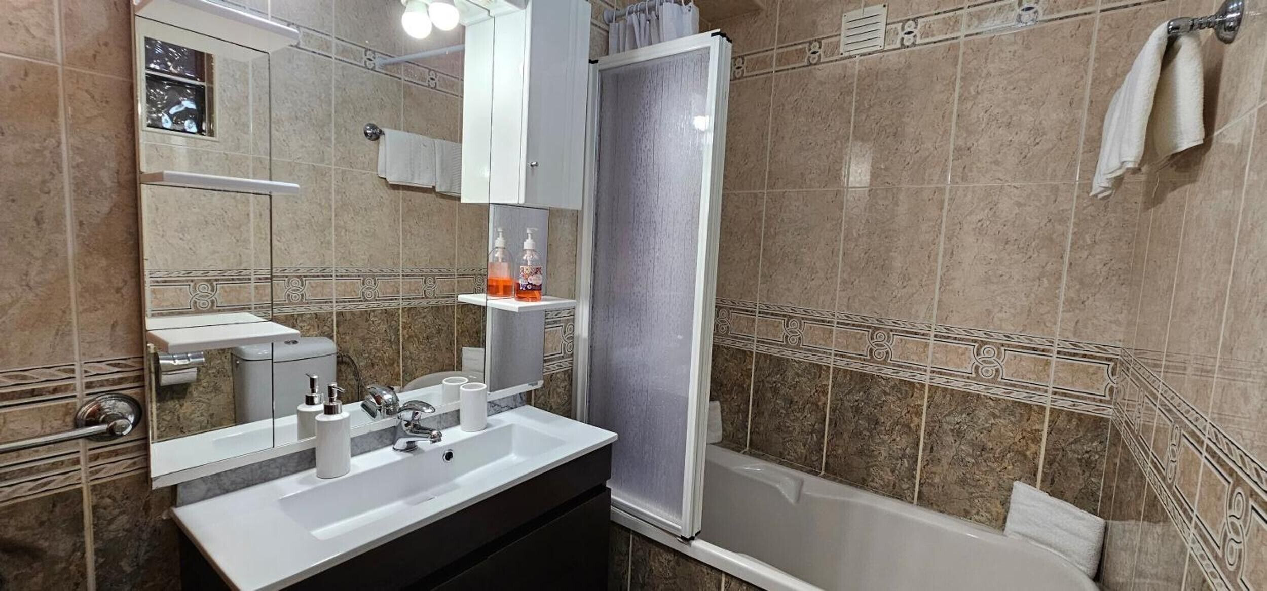 Ein Badezimmer mit Waschbecken, Spiegel, Toilette und Dusche.