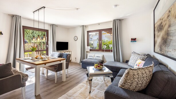 Uma sala de estar moderna com uma mesa de jantar, sofá e televisão.