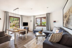 A modern living room with a dining table, sofa, and a TV. - Apartment 'Unit 1' with Shared Terrace, Shared Garden and Wi-Fi (Timmendorfer Strand)