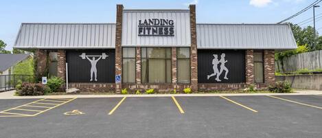 A building with a sign reading "Landing Fitness" and a parking lot in front.