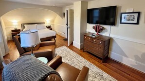 Ein kleines Hotelzimmer mit Bett, Schreibtisch, Fernseher und Kommode.