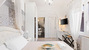 Habitación de hotel con una cama grande, televisión, escritorio con silla y baño visible a través de una puerta abierta.