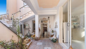 Un interior espacioso con una escalera que lleva a un nivel superior, un pasillo con un arco decorativo y una zona de cocina con frentes de vidrio.