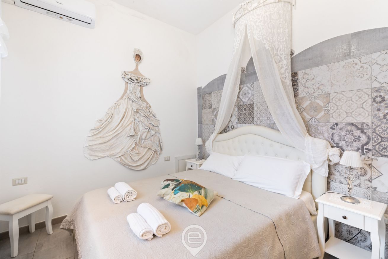 Un dormitorio con cama a dosel, un banco y un perchero en la pared.