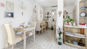 Un comedor con una mesa y sillas de madera, un jarrón con flores y una estantería con artículos para té.