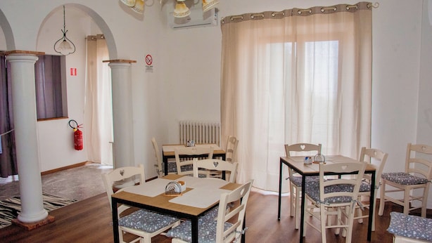 A dining area with two tables, white chairs, a fire extinguisher, and a radiator. - EMERALD ROOM (Castiglione del Lago)