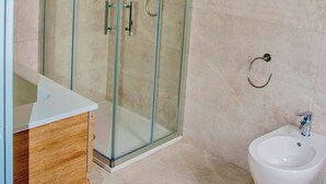 A modern bathroom with a glass-enclosed shower, a wooden vanity, and a white pedestal sink. - EMERALD ROOM (Castiglione del Lago)